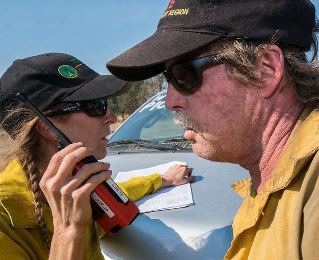 Two firefighters discussing plans over a handheld radio