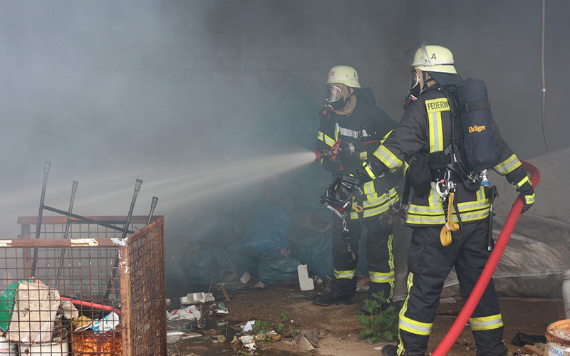 Two firefighters putting out fire in an area full of debris.